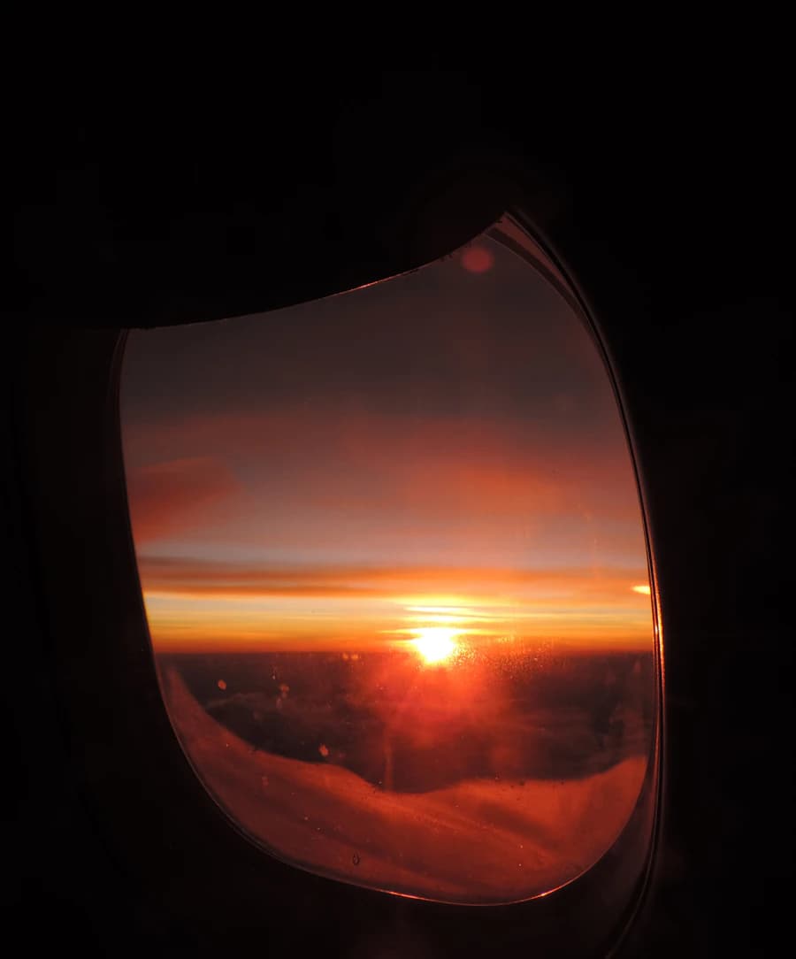 Airplane wing above clouds at sunset