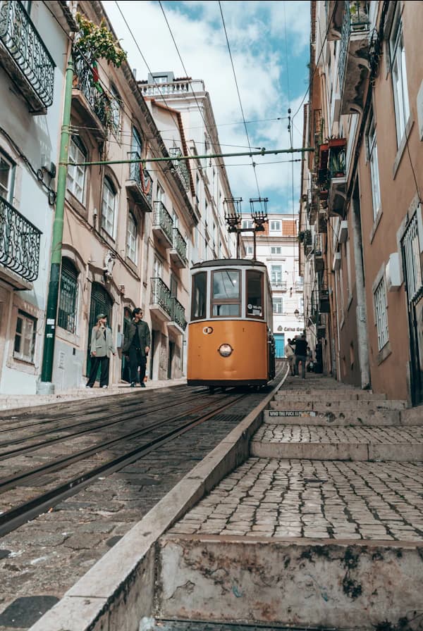 Yellow tram traveling through a narrow Lisbon street